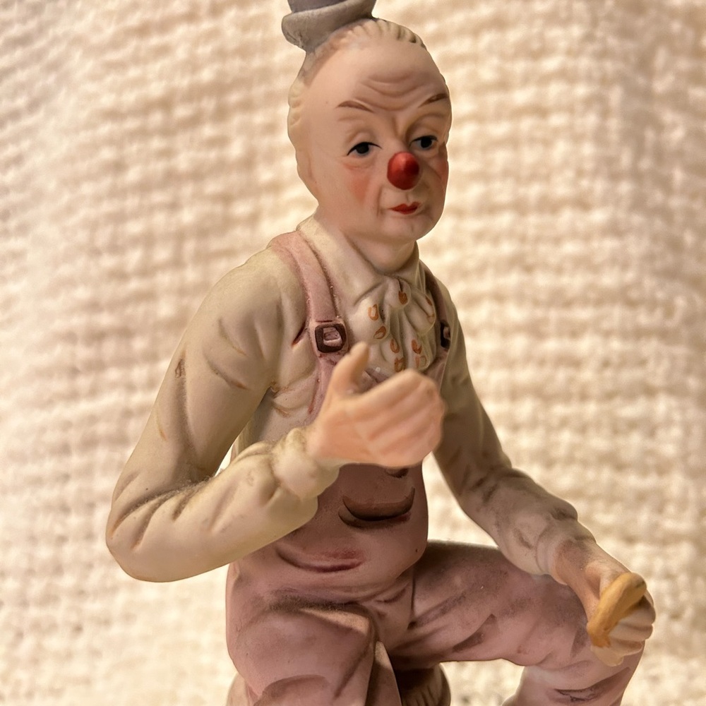Vintage clown figurine. Sitting on a barrel eating.